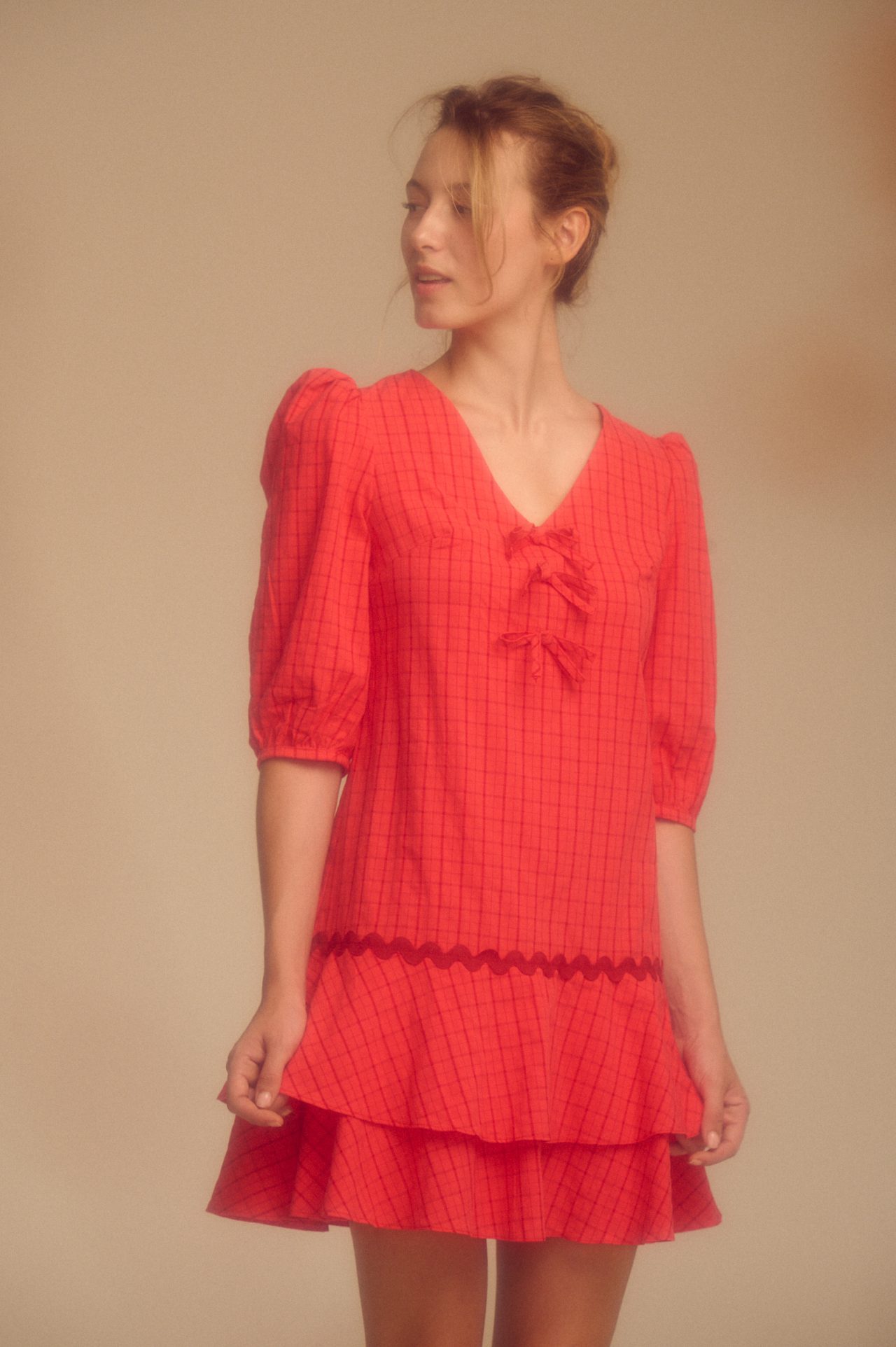 estido corto rojo de estampado a cuadros, con un diseño femenino y llamativo. Presenta mangas abullonadas que aportan volumen y un toque romántico al conjunto. Su corte corto realza la silueta y lo convierte en una prenda fresca y versátil, ideal para ocasiones informales o salidas de día.