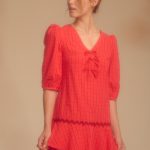 estido corto rojo de estampado a cuadros, con un diseño femenino y llamativo. Presenta mangas abullonadas que aportan volumen y un toque romántico al conjunto. Su corte corto realza la silueta y lo convierte en una prenda fresca y versátil, ideal para ocasiones informales o salidas de día.